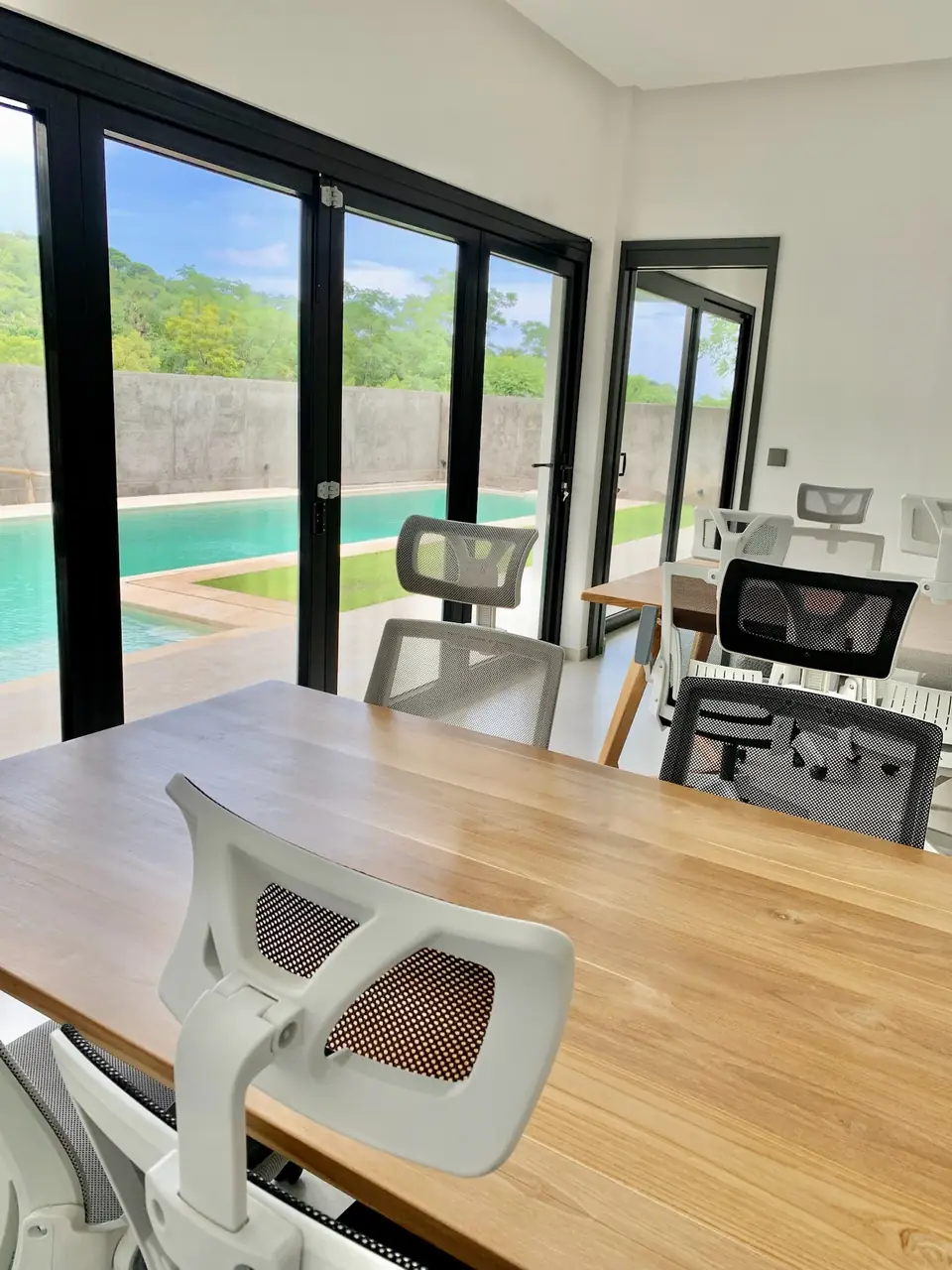 Coworking room with wooden table and pool view